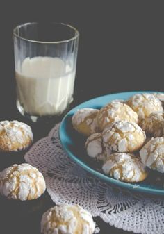 a plate of powdered sugar cookies next to a glass of milk on a table