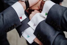 two men in suits are holding hands with one man wearing a watch on his wrist