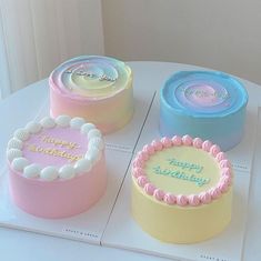 three birthday cakes sitting on top of a white table with happy birthday written on them