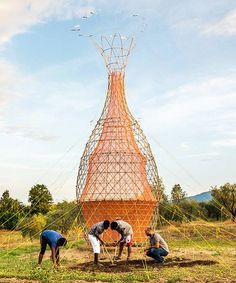 three men working on a sculpture in the middle of a field