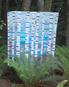 a blue and white quilt sitting on top of a lush green forest