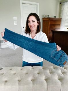 a woman is holding up a pair of jeans