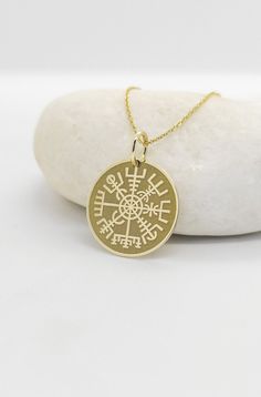 a gold compass necklace on a white rock