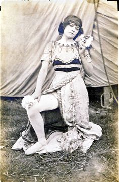 an old black and white photo of a woman sitting on the ground