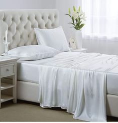 a white bed sitting next to a window in a room with two nightstands on either side