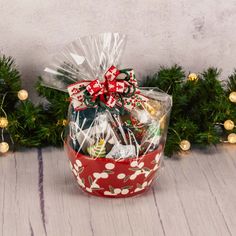 a basket filled with assorted candies and wrapped in clear cellophane on top of a wooden table