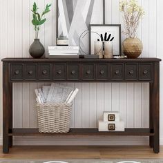 a wooden table topped with lots of pictures and vases next to a white wall