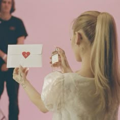 a woman is holding an envelope with a heart on it