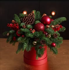 a christmas arrangement in a red container on a table