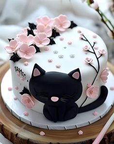 a white cake decorated with black cat and pink flowers