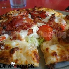 a pizza with bacon, tomatoes and lettuce on it sitting on a plate