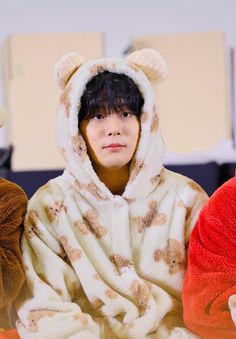 a boy in a bear costume sitting next to two teddy bears wearing animal costumes on the floor