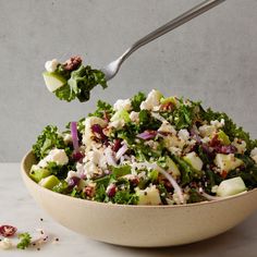 a close up of a salad in a bowl on a table with a silver spoon