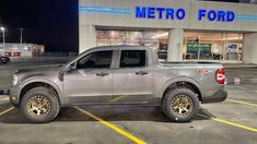 a silver truck parked in front of a metro ford dealership