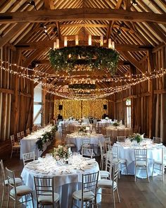 the inside of a barn with tables and chairs set up for a formal dinner or function