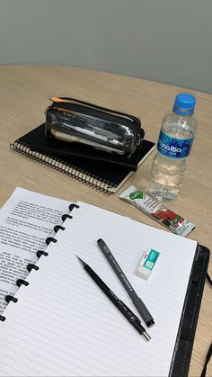 a notebook, pen and water bottle sitting on a table