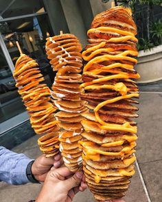 there are several large stacks of cheese and bread on the sticks in front of a building