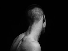 black and white photograph of a man's back with no shirt on in the dark