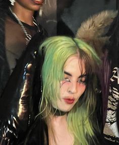 a woman with green hair and piercings standing in front of other women wearing black clothing