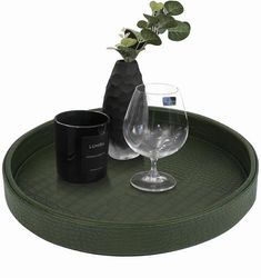 a green tray with a vase and two wine glasses sitting on it next to a black mug