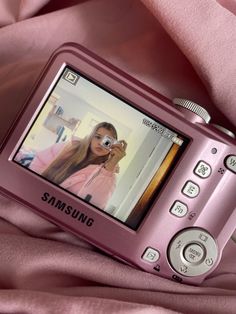 a pink cell phone laying on top of a bed next to a pink sheet with a woman's face