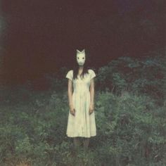 a woman in a white dress with a cat mask on her head and the words but daring, this is not wonderlandland