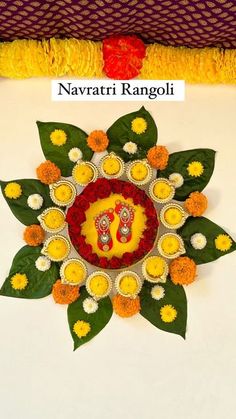 an intricately decorated wall hanging on the side of a white table with yellow and red flowers