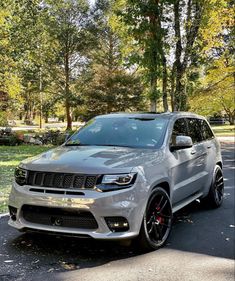 a silver jeep is parked on the side of the road in front of some trees