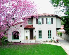 a white house with pink flowers on the trees