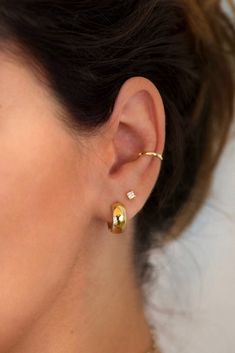 a close up of a woman's ear wearing gold earrings