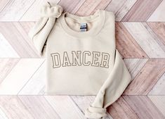 You will love this dancer sweatshirt! It is the perfect sweatshirt to wear to dance practice and makes a great gift for dancers! PRODUCTION TIME: 1-3 business days SHIPPING TIME: 2-5 business days  PRODUCT DESCRIPTION: Ideal for any situation, a unisex heavy blend crewneck sweatshirt is pure comfort. These garments are made from polyester and cotton. This combination helps designs come out looking fresh and beautiful. The collar is ribbed knit, so it retains its shape even after washing. There are no itchy side seams on these sweaters.  50% cotton, 50% polyester Medium-heavy fabric (8.0 oz/yd² (271.25 g/m Loose fit Sewn-in label Runs true to size * For Sweatshirt Sizes Please refer to the Listing Image. CARE INSTRUCTION: Machine wash: warm (max 40C or 105F); Non-chlorine: bleach as needed; Casual Letter Print Sweatshirt For Dance, Cotton Hip Hop Sweatshirt For Dance Class, Dance Merchandise Ideas, Crew Neck Sweatshirt With Letter Print For Dance, Hip Hop Long Sleeve Sweatshirt For Dance, Casual Crew Neck Sweatshirt For Dance, Fall Dance Cotton Sweatshirt, Cotton Sweatshirt For Dance In Fall, Fall Cotton Sweatshirt For Dance