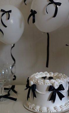 a white cake with black bows and balloons