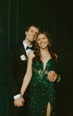 a man in a tuxedo standing next to a woman in a green dress