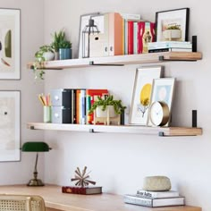 a desk with some books and pictures on the wall above it, along with other office supplies