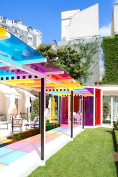 an outdoor covered patio with colorful walls and umbrellas on the roof, surrounded by grass