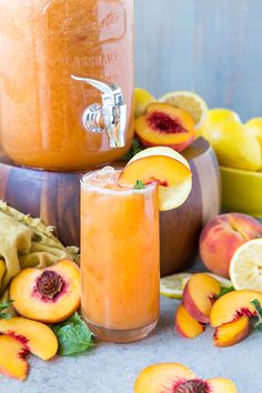 a glass filled with orange juice next to sliced peaches