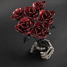 a bunch of red roses sitting on top of a black table next to screwdrivers