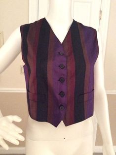 Luxurious silk vest to layer over a blouse to create the Gigli iconic layered romantic look. The jewel tones blend with other Gigli pieces so well. Bronze, purple, burgundy, and black stripes allow it to mix with a variety of colors. The back of the vest is a bronze color. Working pockets on the front of the V notched front of the vest. Five black marbled flat button front closure Made in ItalyFully lined in bronze rayon.Measurements:Length - 21”Bust - 35”Waist - 32” Fitted Purple Silk Tops, Formal Silk Vest For Spring, Fitted Silk Vest For Workwear, Fitted Silk Vest For Work, Silk Fitted Vest For Formal Occasions, Formal Fitted Silk Vest, Formal Silk Fitted Vest, Fitted Silk Chic Vest, Fitted Chic Silk Vest