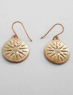 pair of gold earrings with sun design on them