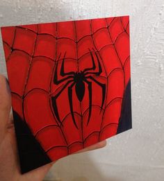 a hand holding up a red and black spider - man card