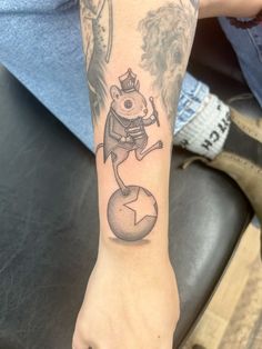 a person with a tattoo on their arm holding a ball and pointing to the sky