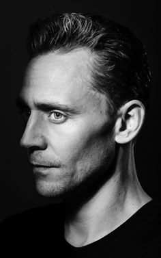 a black and white photo of a man with ear piercings looking at the camera