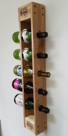 a wooden wine rack with six bottles in it and two on the wall behind it