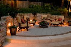 an outdoor seating area with chairs and fire pit in the middle, surrounded by stone steps