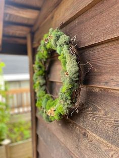 a wreath is hanging on the side of a wooden building with moss growing in it