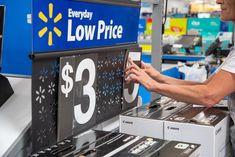 a woman in a store checking out the price of a low price sign with her hands