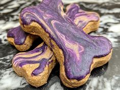 two purple and gold dog treats on a marble surface with white swirls around them