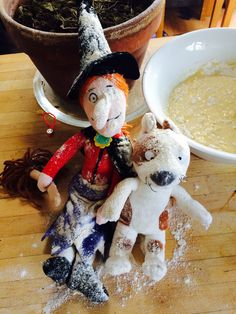 two stuffed animals sitting on top of a wooden table next to a potted plant