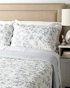 a bed with blue and white bedspread in a bedroom next to a night stand