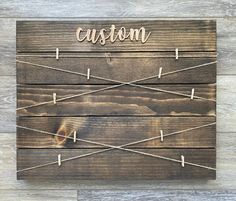 a wooden sign that says custom on it with clothes pins attached to the wood planks